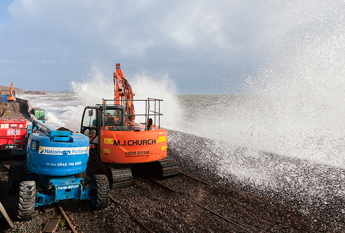 Machinery and workers get a soaking as waves constantly batter what's left of the sea wall at Dawlish, Devon